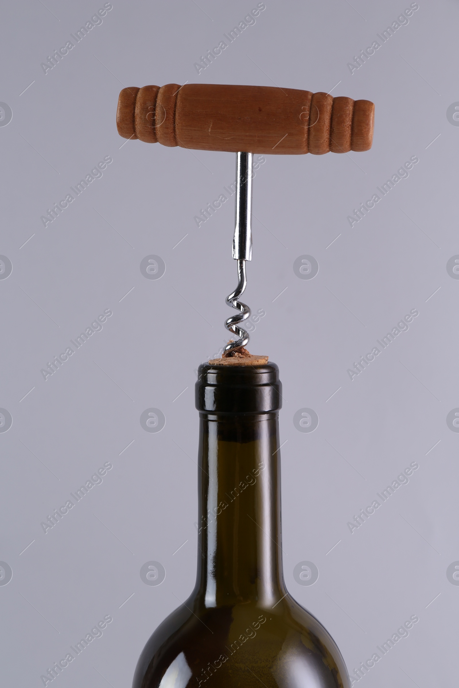 Photo of Wine bottle with corkscrew on grey background