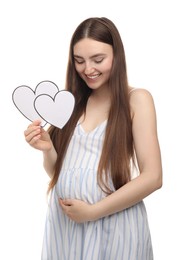 Photo of Expecting twins. Pregnant woman holding two paper cutouts of hearts on white background