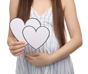 Expecting twins. Pregnant woman holding two paper cutouts of hearts on white background, closeup