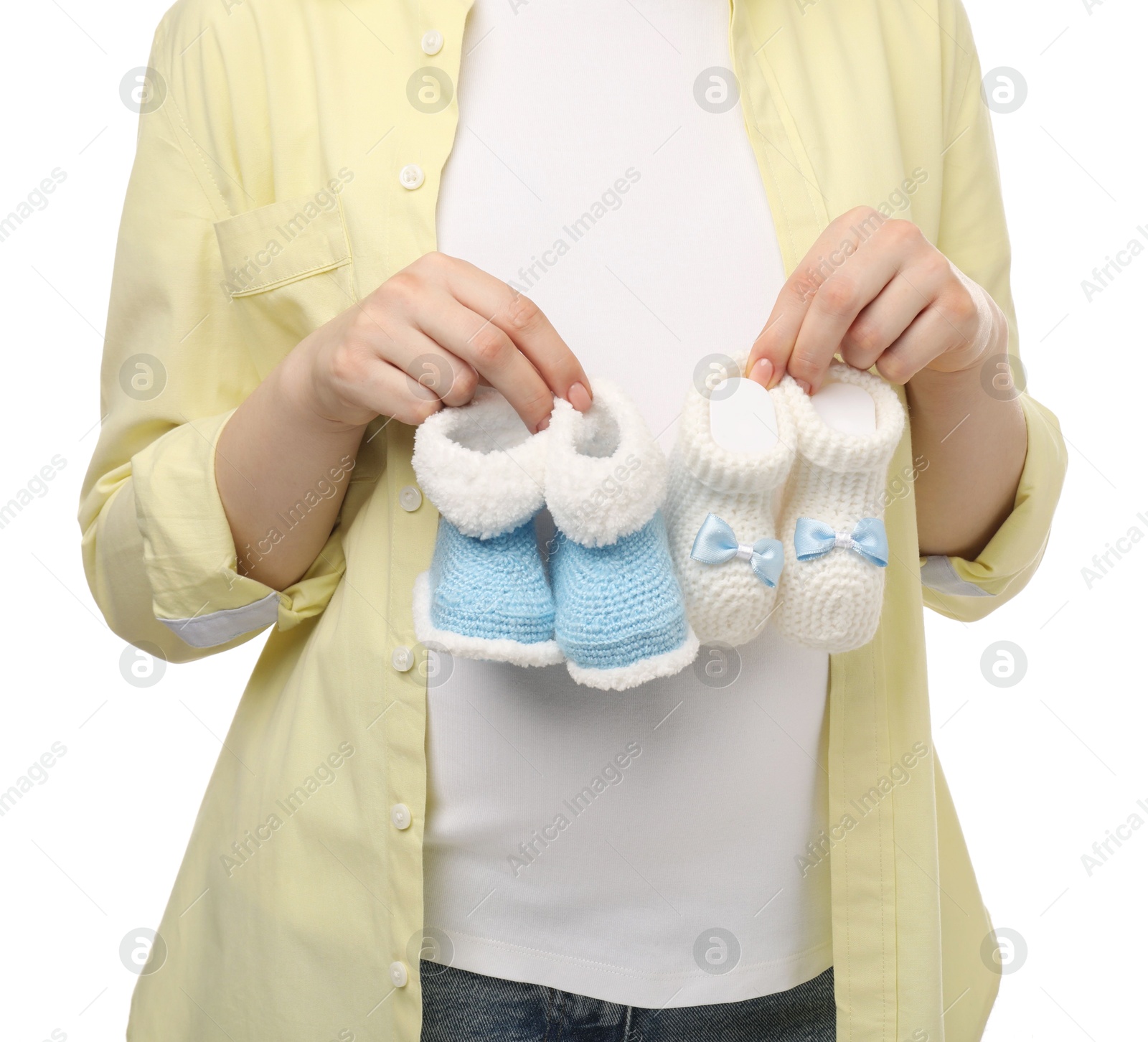 Photo of Expecting twins. Pregnant woman holding two pairs of baby shoes on white background, closeup