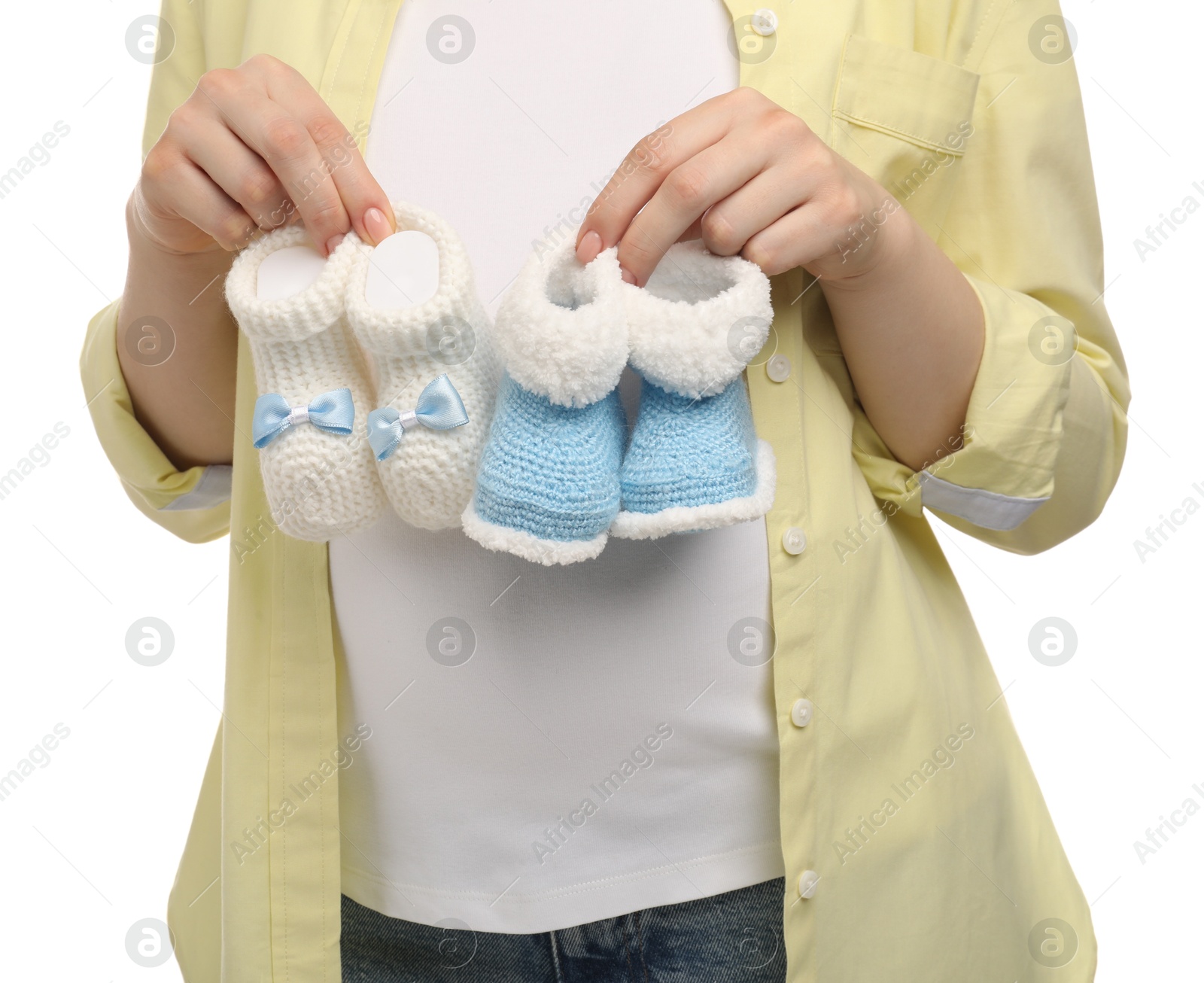 Photo of Expecting twins. Pregnant woman holding two pairs of baby shoes on white background, closeup