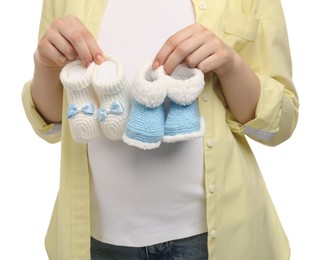 Photo of Expecting twins. Pregnant woman holding two pairs of baby shoes on white background, closeup