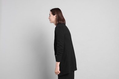 Woman with poor posture on gray background