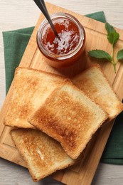 Photo of Delicious toasts and jam on wooden table, top view