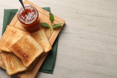 Delicious toasts and jam on wooden table, top view. Space for text