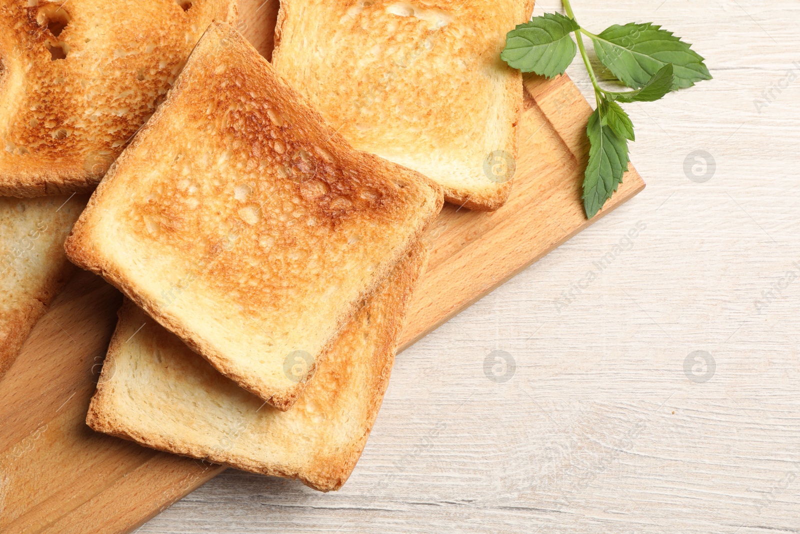 Photo of Slices of delicious toasted bread on wooden table, top view