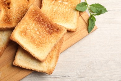 Photo of Slices of delicious toasted bread on wooden table, top view