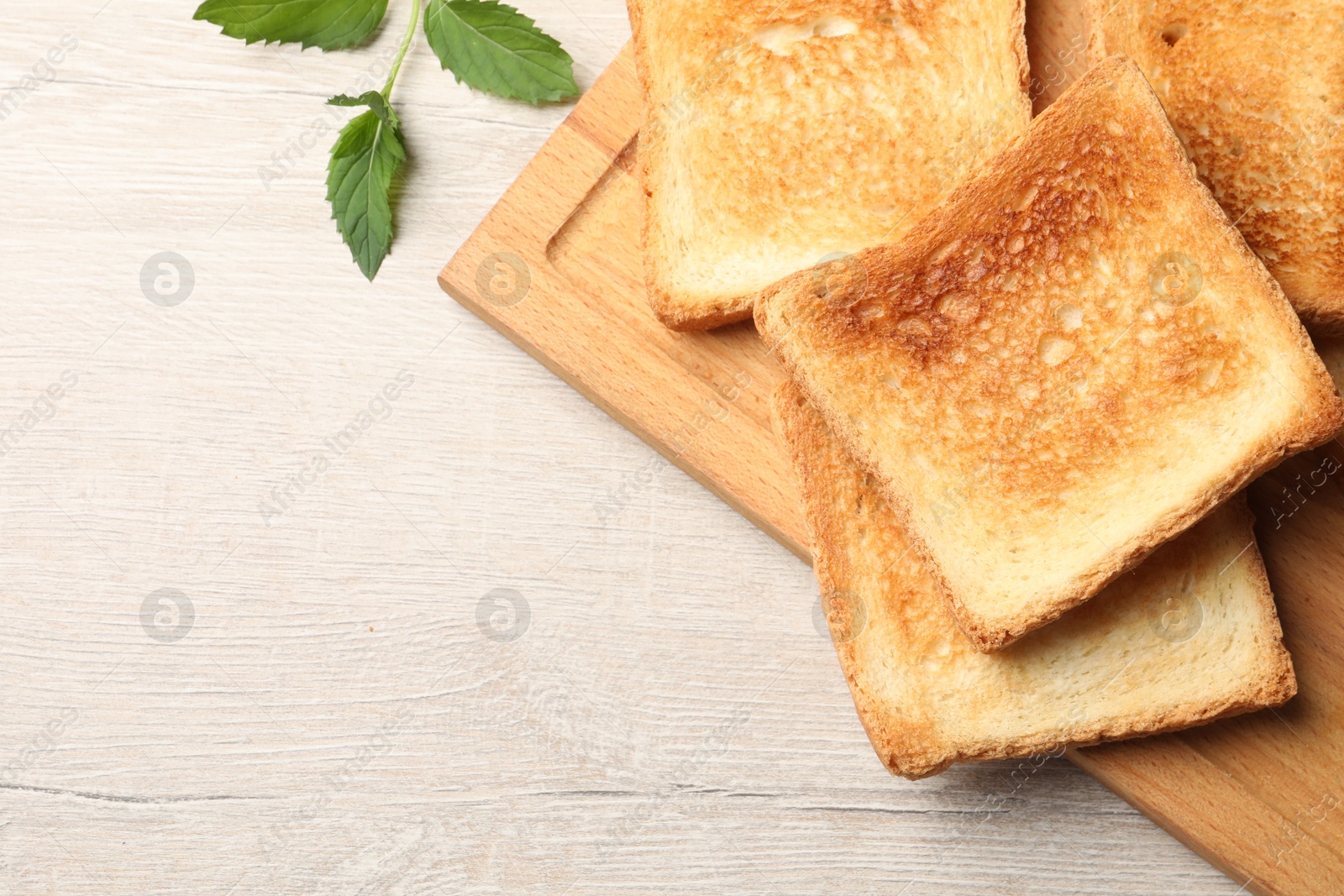 Photo of Slices of delicious toasted bread on wooden table, top view. Space for text