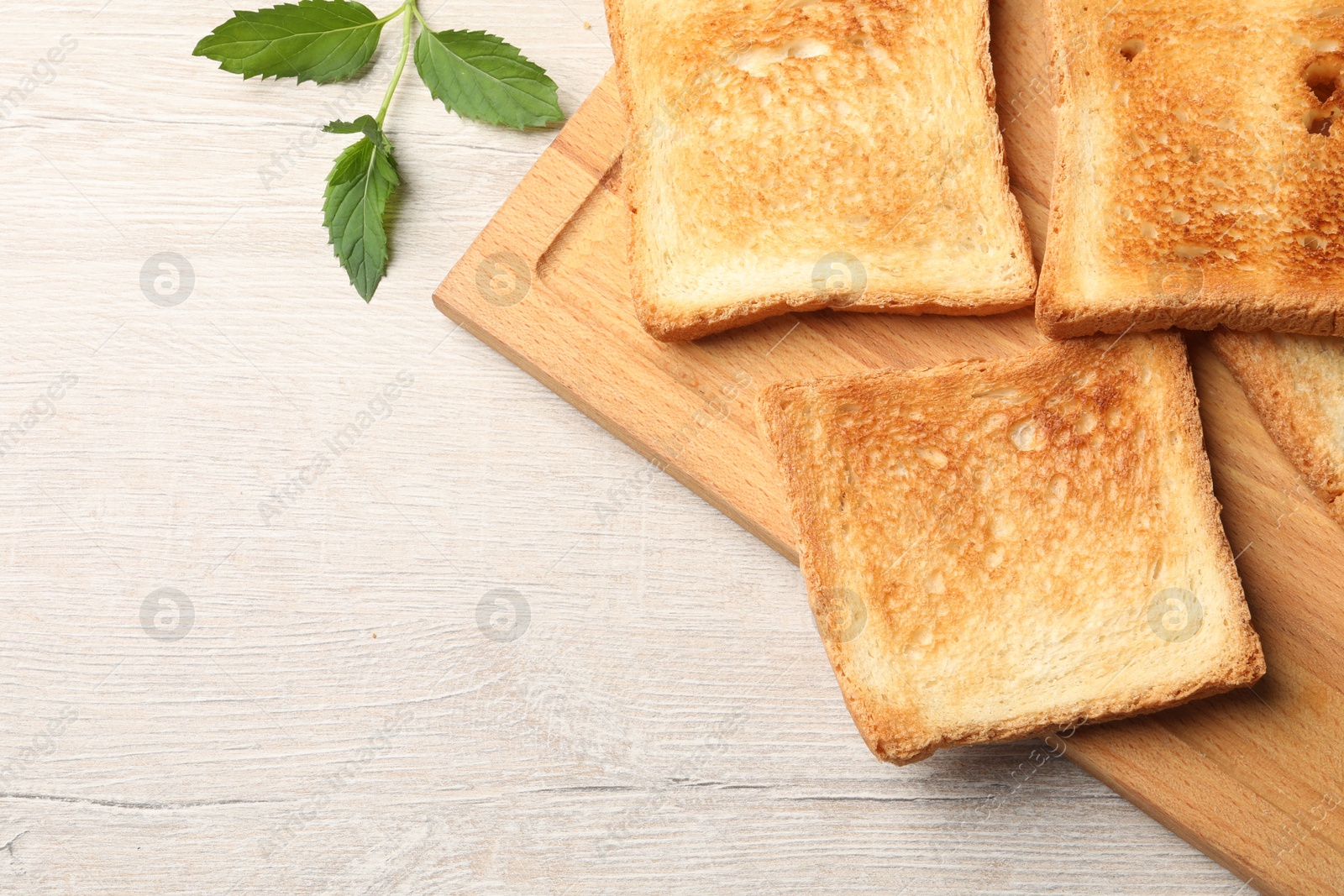 Photo of Slices of delicious toasted bread on wooden table, top view. Space for text