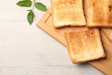 Photo of Slices of delicious toasted bread on wooden table, top view. Space for text