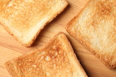 Slices of delicious toasted bread on wooden table, top view