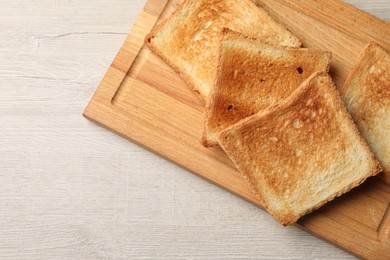 Photo of Slices of delicious toasted bread on wooden table, top view. Space for text