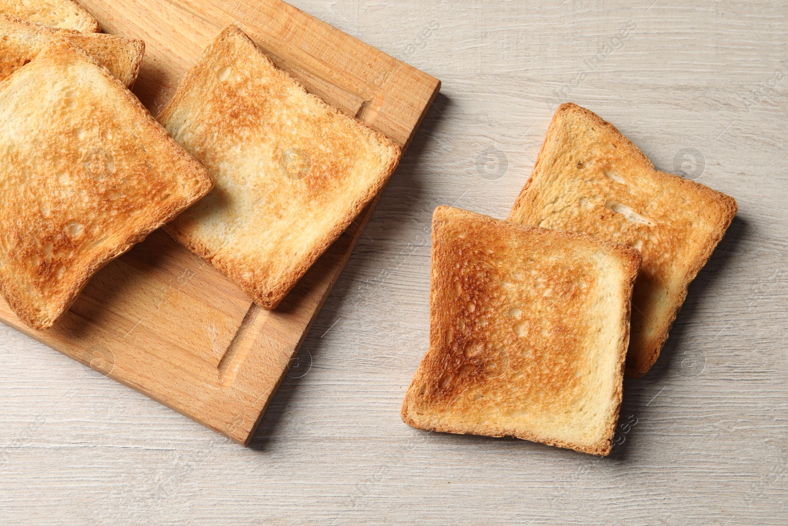 Photo of Slices of delicious toasted bread on wooden table, top view