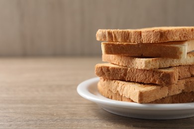 Photo of Stack of delicious toasted bread slices on wooden table. Space for text