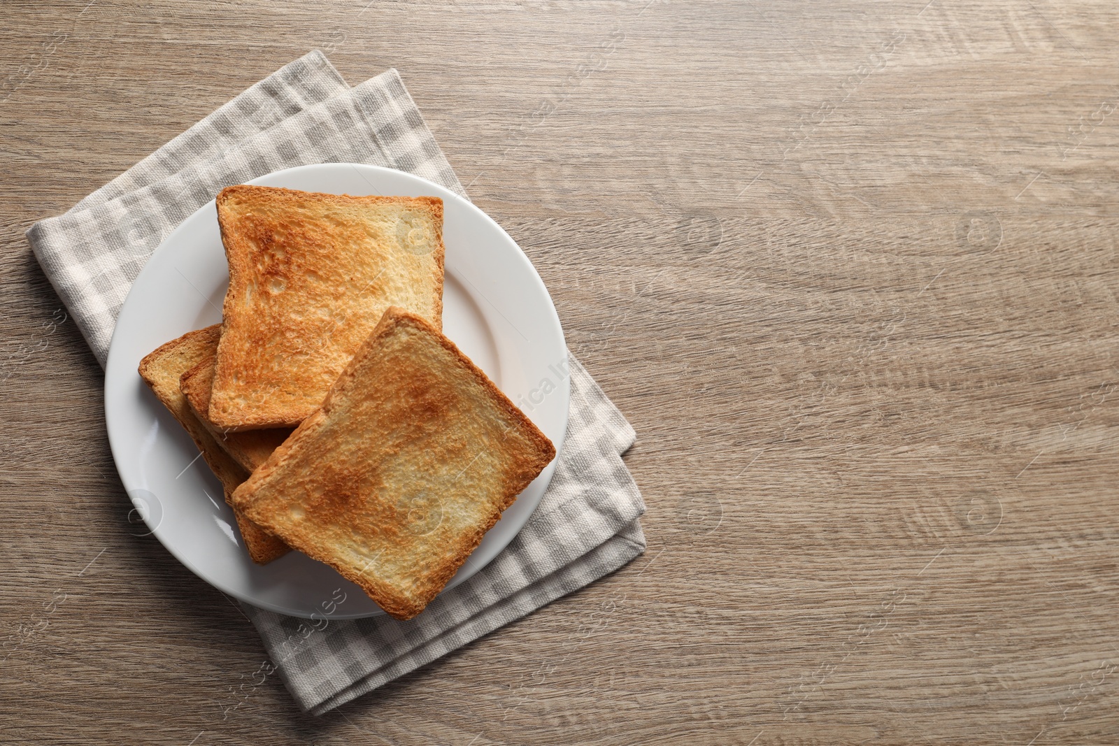 Photo of Slices of delicious toasted bread on wooden table, top view. Space for text