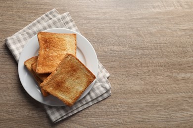 Photo of Slices of delicious toasted bread on wooden table, top view. Space for text