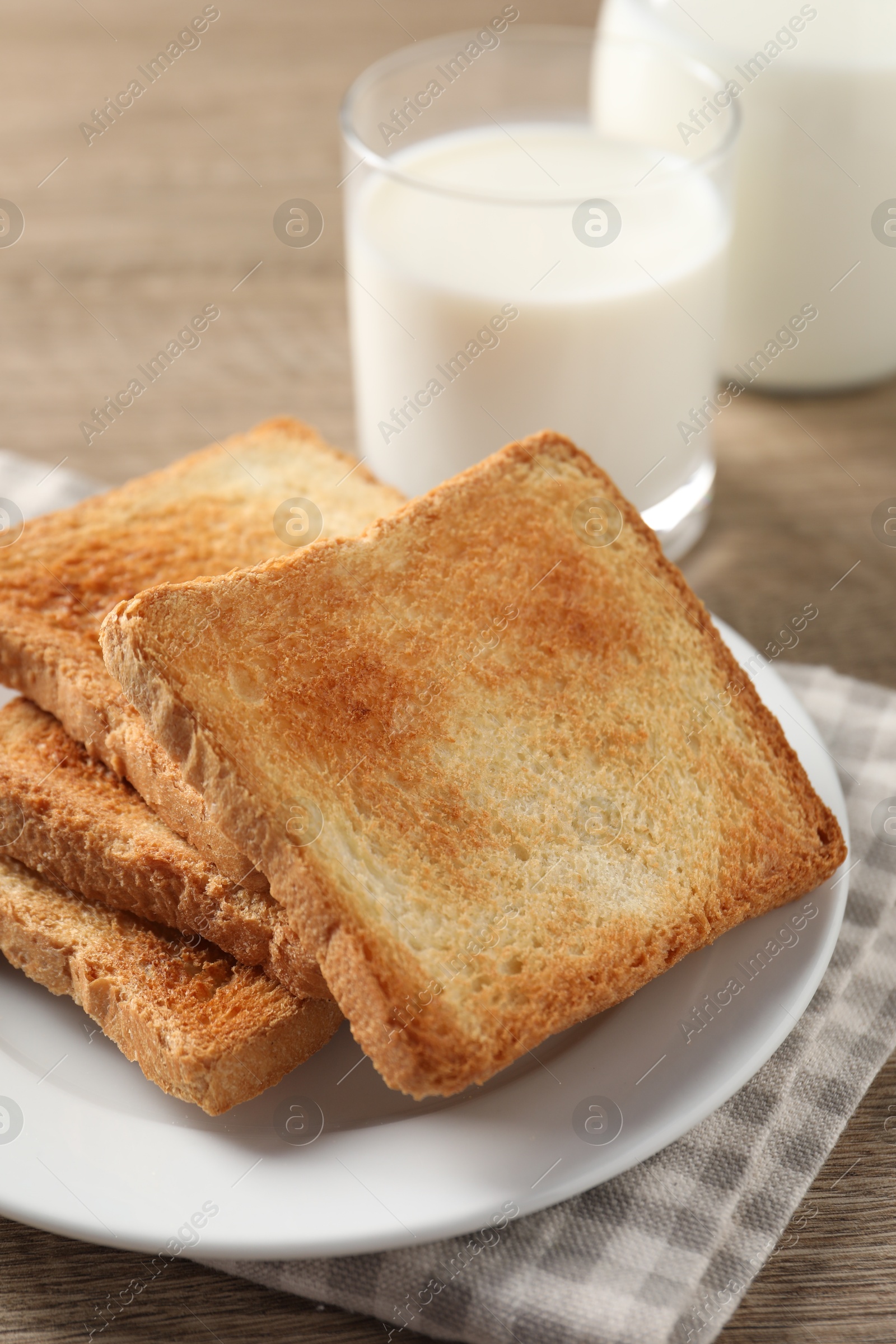 Photo of Delicious toasts with milk on wooden table, closeup