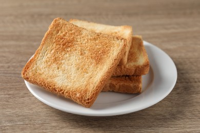 Photo of Slices of delicious toasted bread on wooden table, closeup