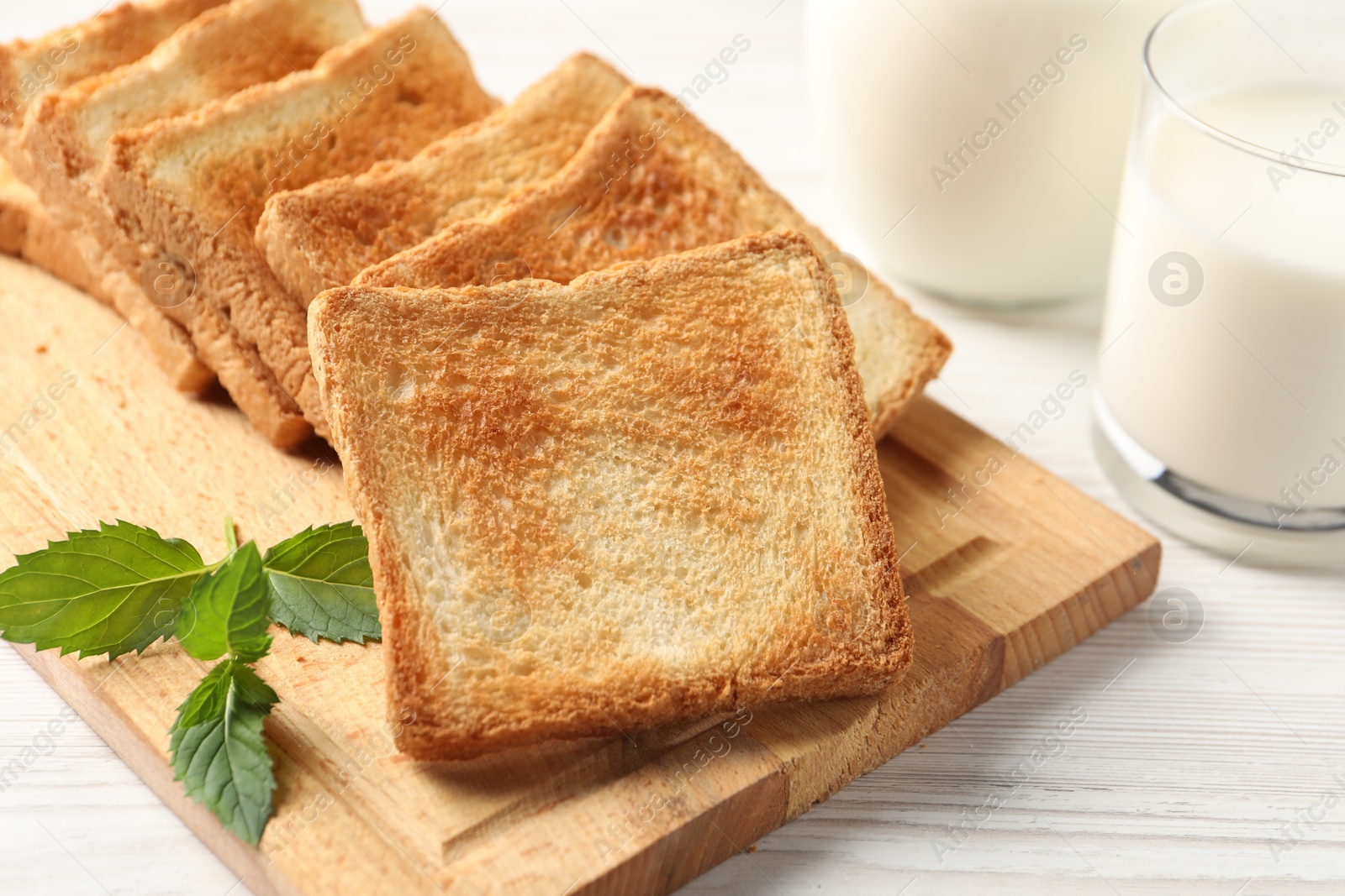 Photo of Delicious toasts with milk on white wooden table, closeup