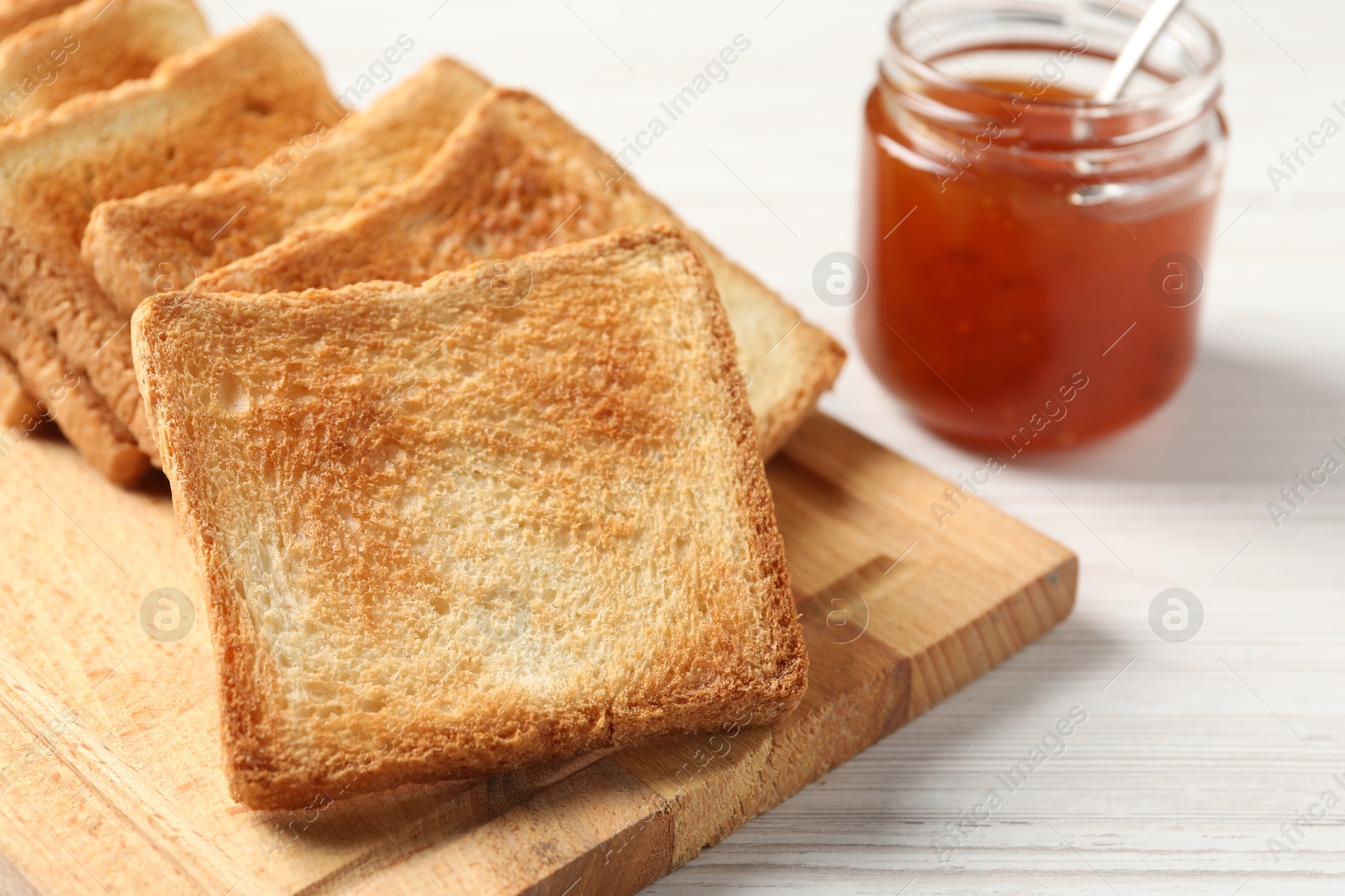 Photo of Delicious toasts and jam on white wooden table, closeup