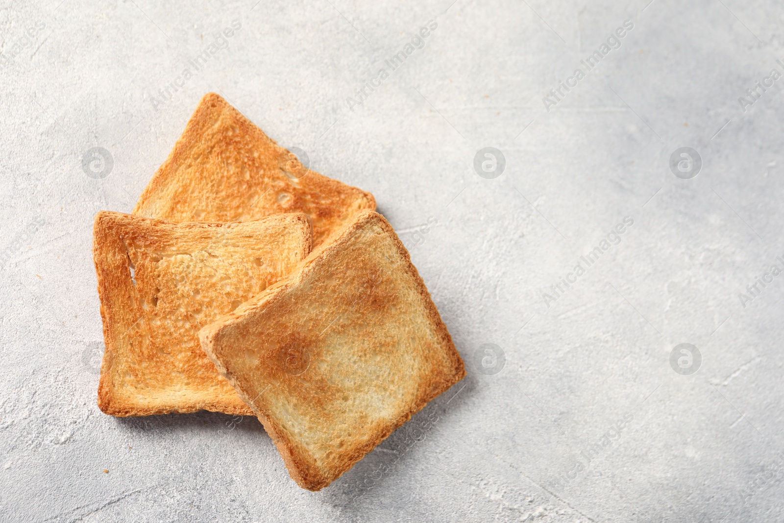 Photo of Slices of delicious toasted bread on light table, top view. Space for text