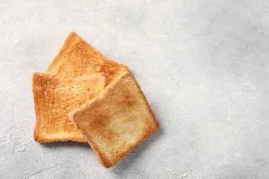 Photo of Slices of delicious toasted bread on light table, top view. Space for text