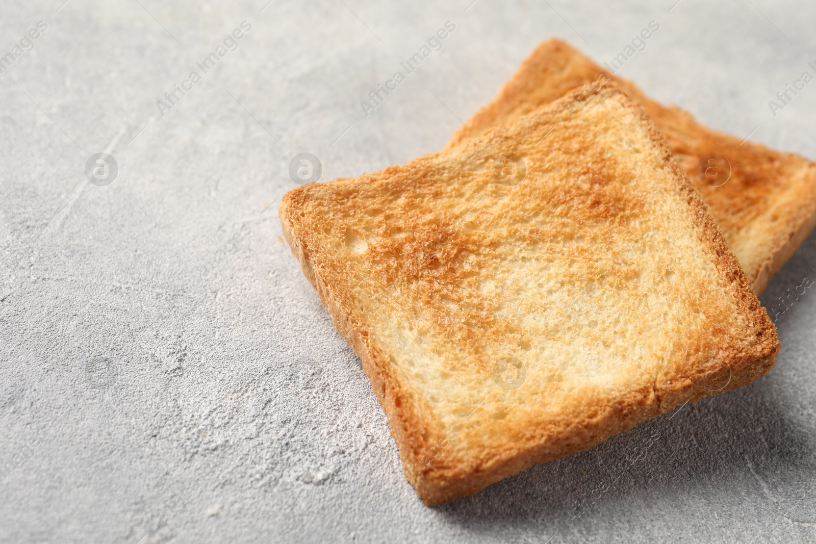 Photo of Slices of delicious toasted bread on light table, closeup