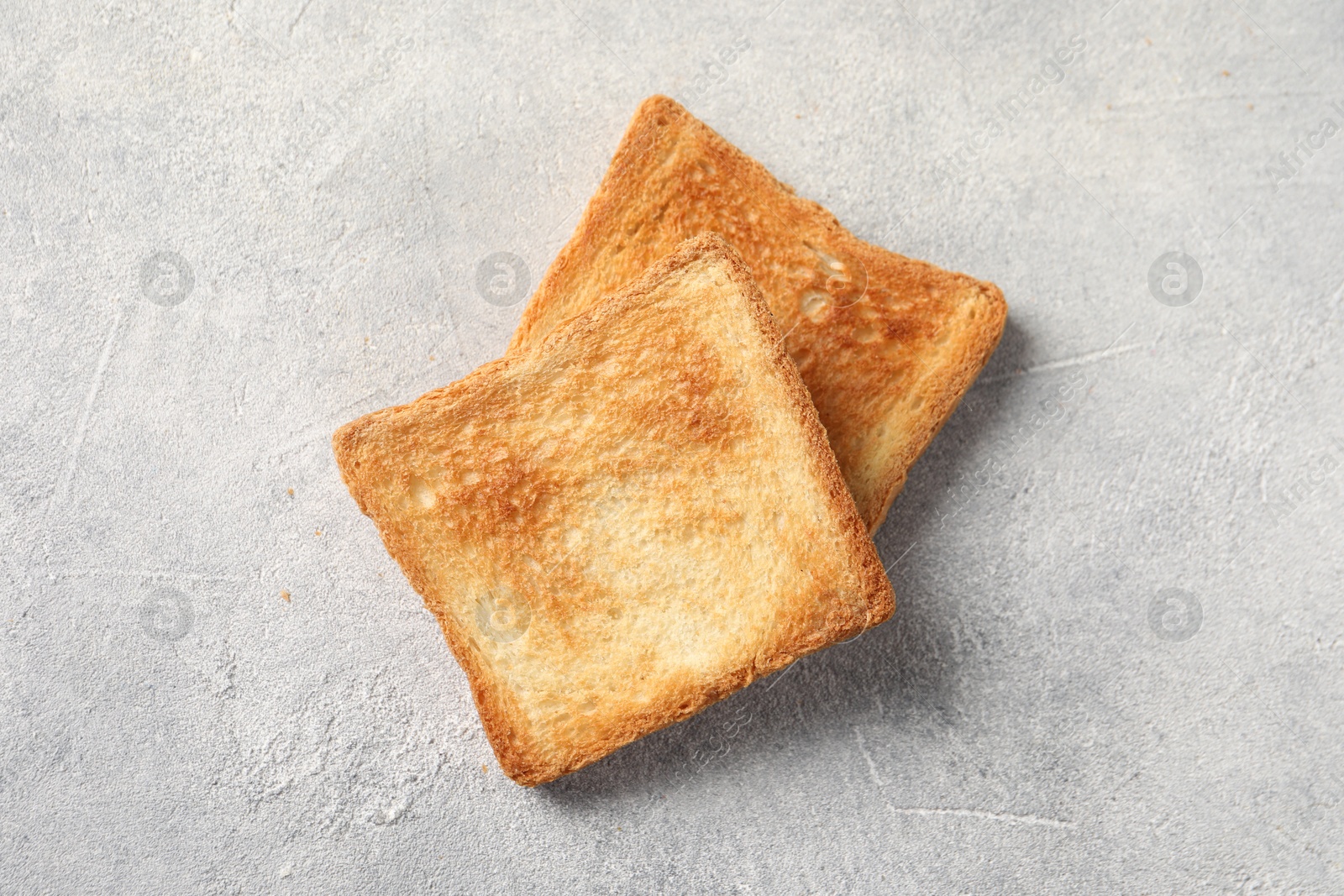 Photo of Slices of delicious toasted bread on light table, top view