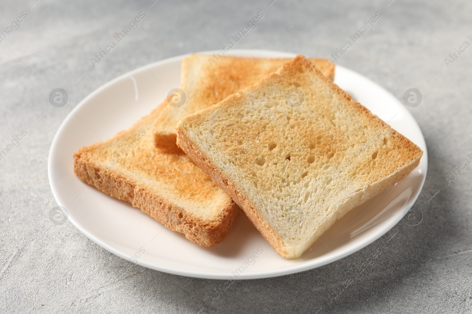 Photo of Slices of delicious toasted bread on light table, closeup