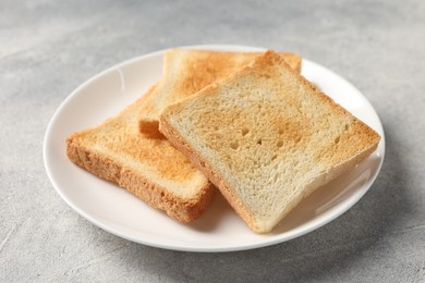 Photo of Slices of delicious toasted bread on light table, closeup