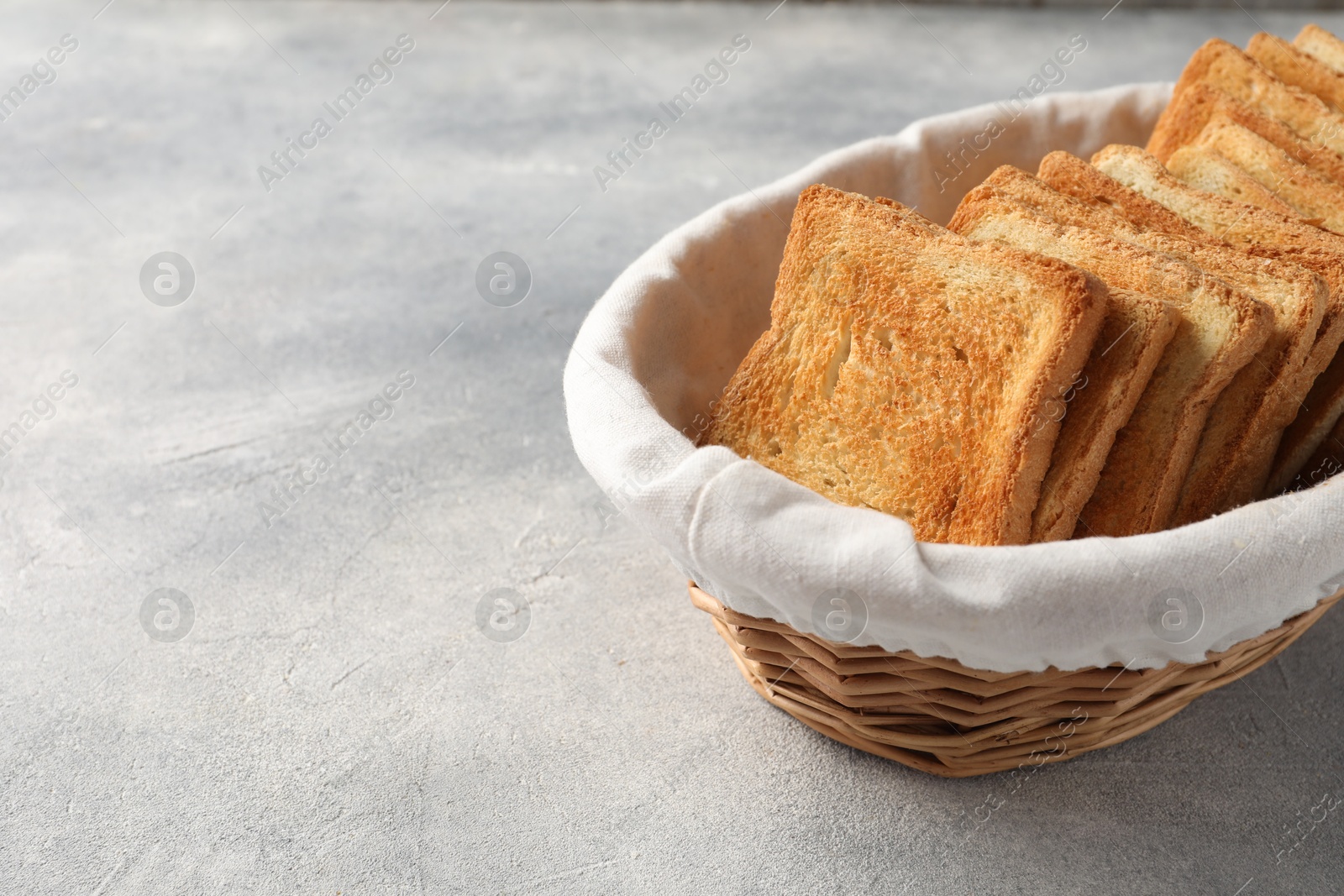 Photo of Delicious toasts in basket on light table. Space for text