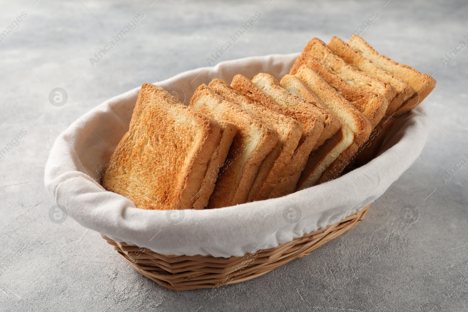 Photo of Delicious toasts in basket on light table