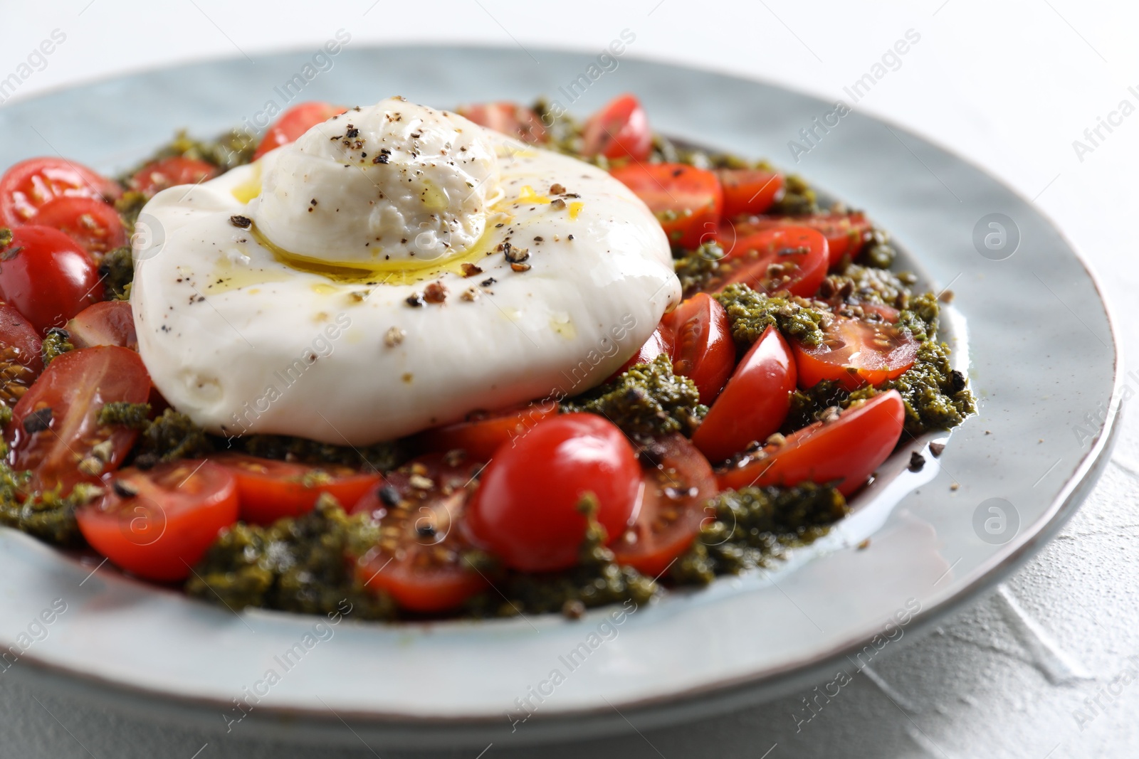 Photo of Fresh delicious burrata salad on white table, closeup