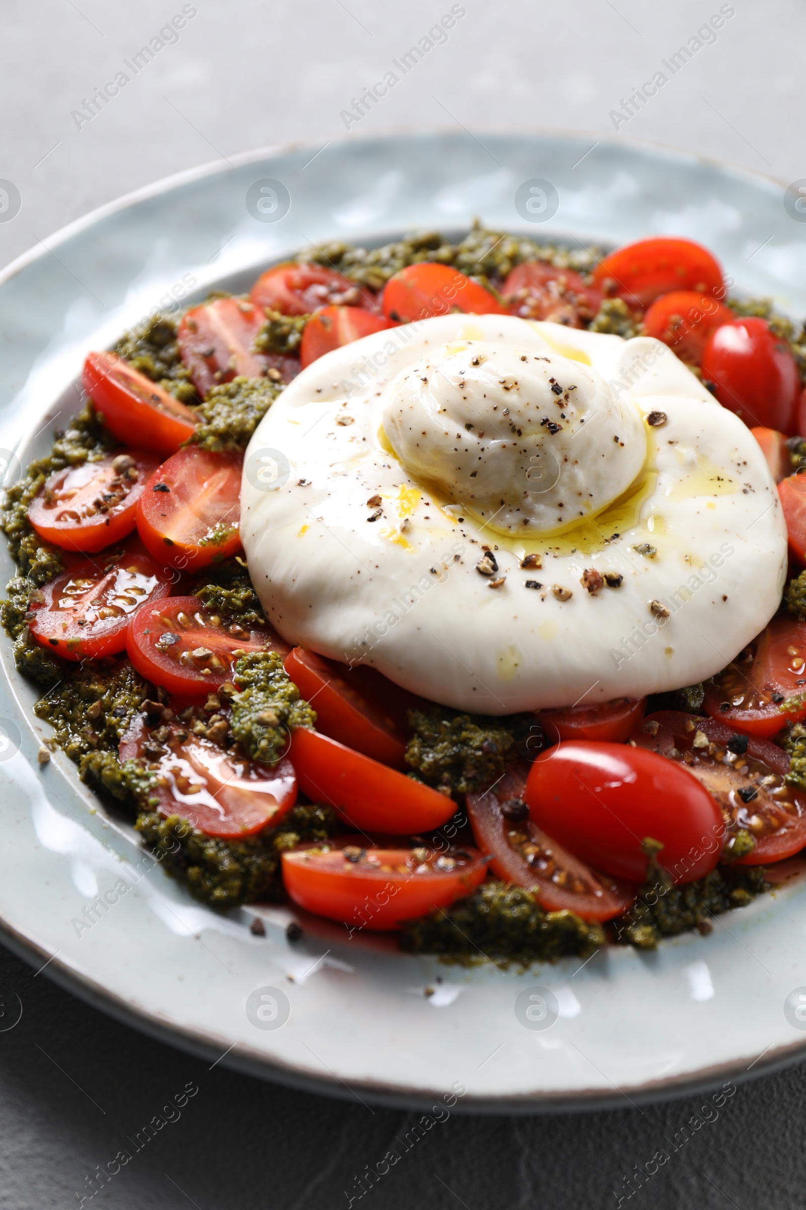 Photo of Fresh delicious burrata salad on light grey table, closeup