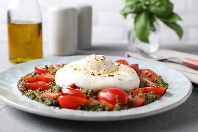 Fresh delicious burrata salad on light grey table, closeup