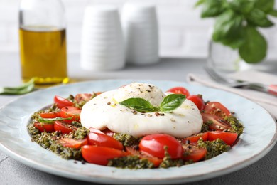 Fresh delicious burrata salad on light grey table, closeup