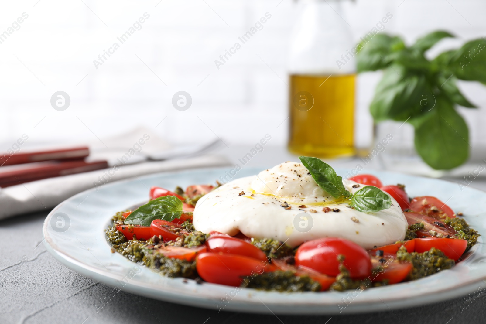 Photo of Fresh delicious burrata salad on light grey table, closeup