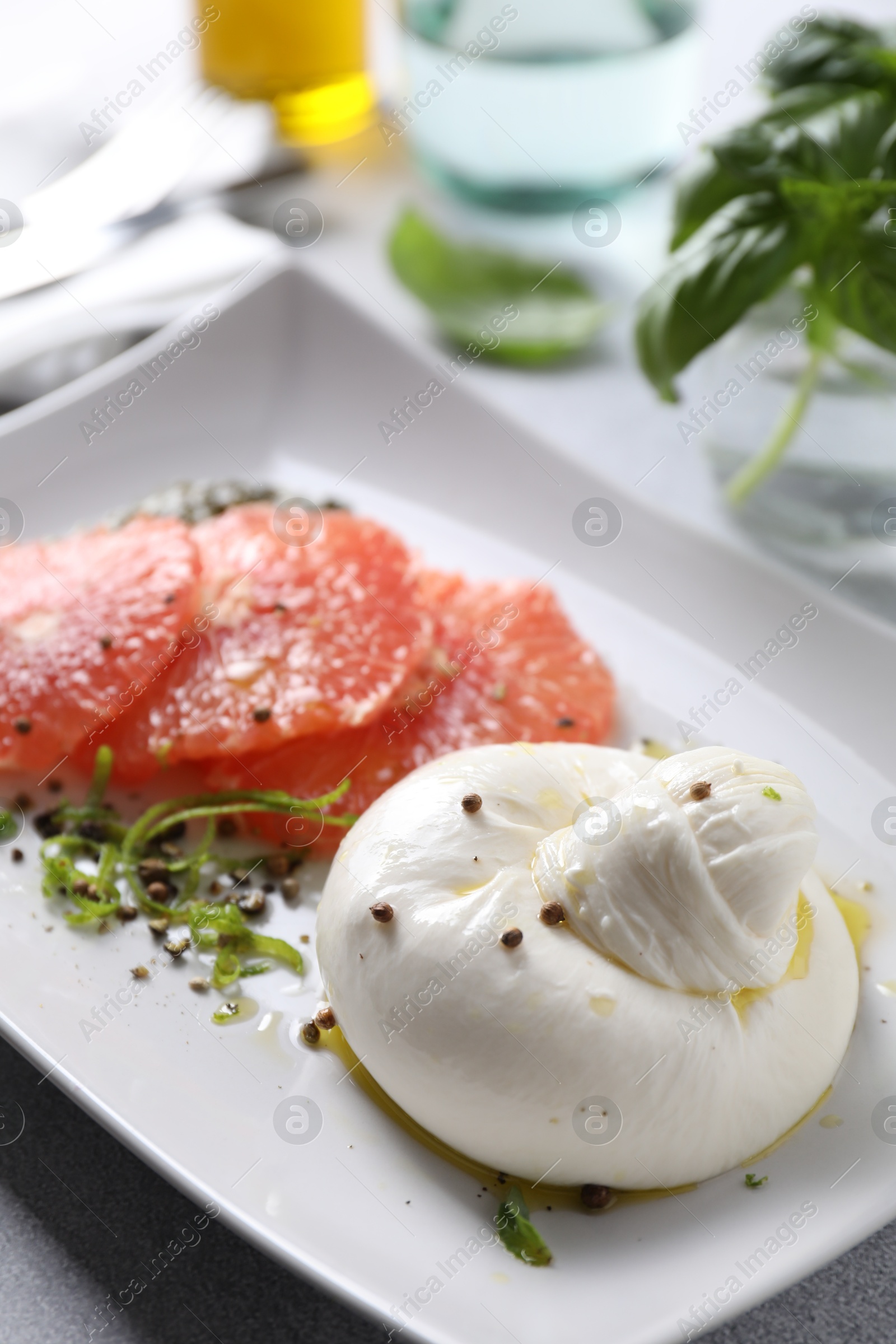 Photo of Delicious burrata cheese, grapefruit and spices on table, closeup