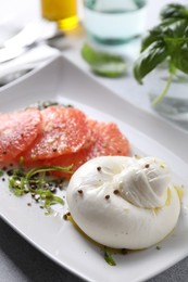 Photo of Delicious burrata cheese, grapefruit and spices on table, closeup