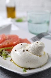 Photo of Delicious burrata cheese, grapefruit and spices on table, closeup