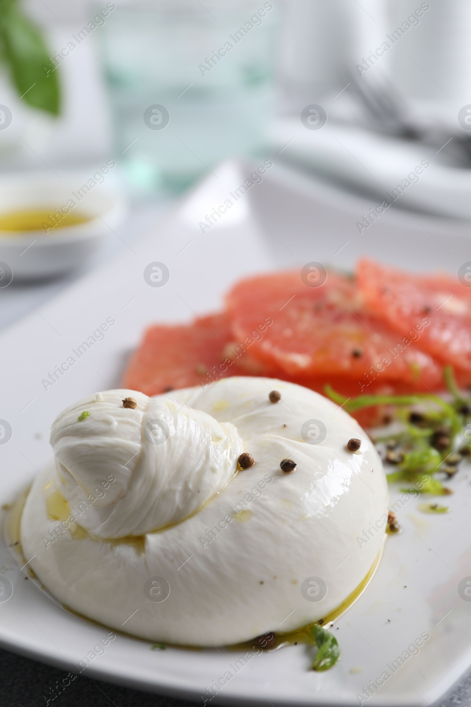 Photo of Delicious burrata cheese, grapefruit and spices on table, closeup