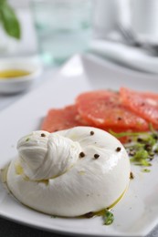 Photo of Delicious burrata cheese, grapefruit and spices on table, closeup