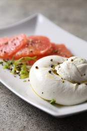 Photo of Delicious burrata cheese, grapefruit and spices on grey table, closeup