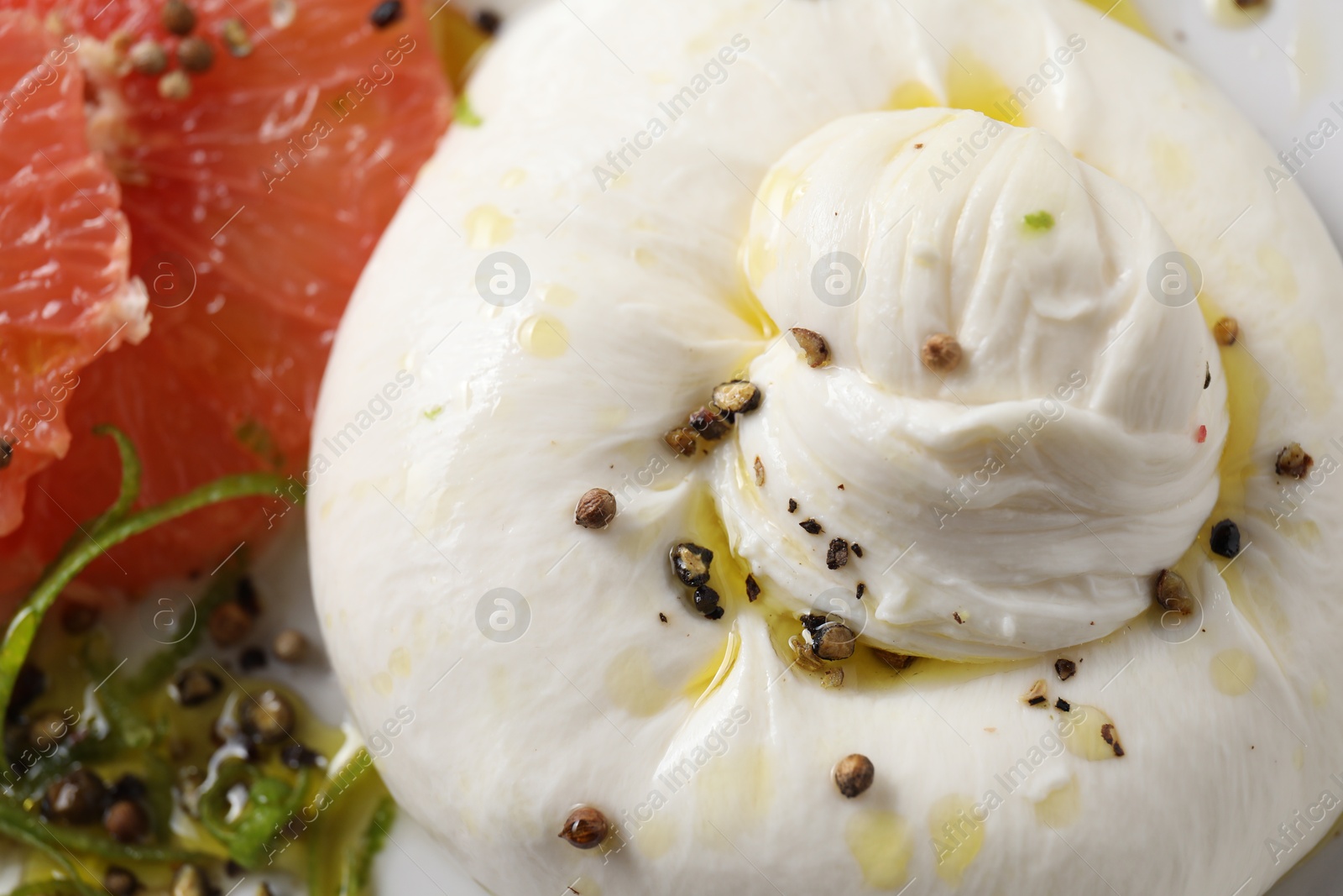 Photo of Delicious burrata cheese, grapefruit and spices on plate, closeup