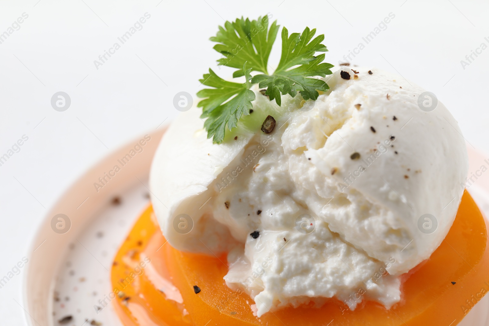 Photo of Delicious burrata cheese, tomato and parsley on table, closeup