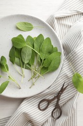 Photo of Fresh sage leaves and scissors on light wooden table, flat lay