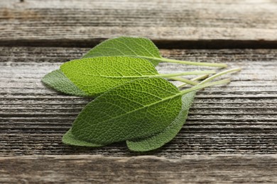 Photo of Fresh sage leaves on wooden table, closeup