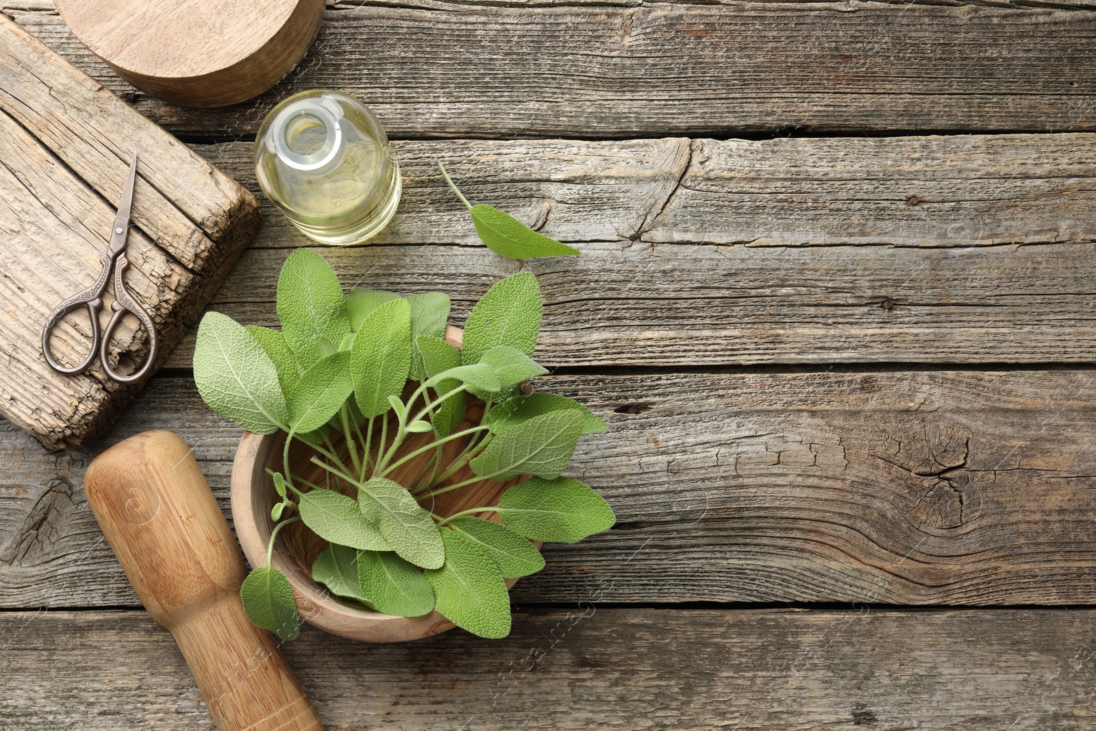 Photo of Fresh sage leaves, mortar, pestle, bottle of oil and scissors on wooden table, flat lay. Space for text