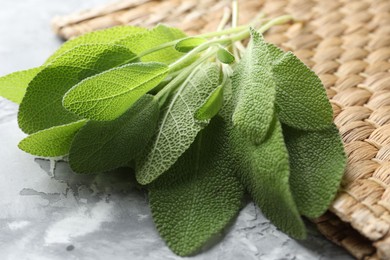 Photo of Fresh sage leaves on gray textured table, closeup