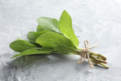 Photo of Bunch of fresh sage leaves on gray textured table, closeup